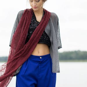 Peut inclure: Une femme portant une &eacute;charpe en dentelle bordeaux, un cardigan gris, un haut en dentelle noire et un pantalon bleu.