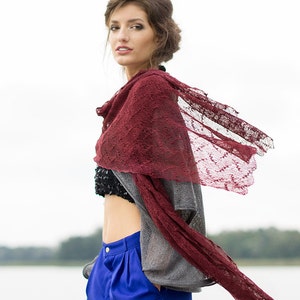 Peut inclure: Une femme portant un ch&acirc;le en dentelle bordeaux sur un pull gris et un pantalon bleu. Le ch&acirc;le flotte au vent.