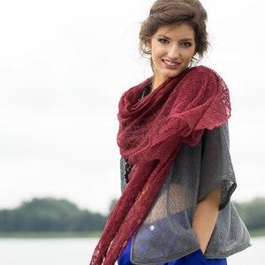 Peut inclure: Une femme portant un haut gris avec une &eacute;charpe en dentelle rouge, un pantalon bleu et un collier en or. Elle sourit et regarde la cam&eacute;ra.