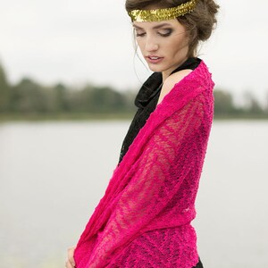 May include: A woman wearing a black dress with a pink lace shawl draped over her shoulders. She is wearing a gold headband with sequins.
