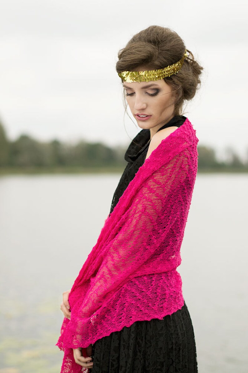 May include: A woman wearing a black dress with a pink lace shawl draped over her shoulders. She is wearing a gold headband with sequins.