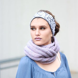 Pode incluir: Uma mulher vestindo uma camisa azul com uma echarpe de malha roxa e uma faixa de cabeça com padrão preto e branco.
