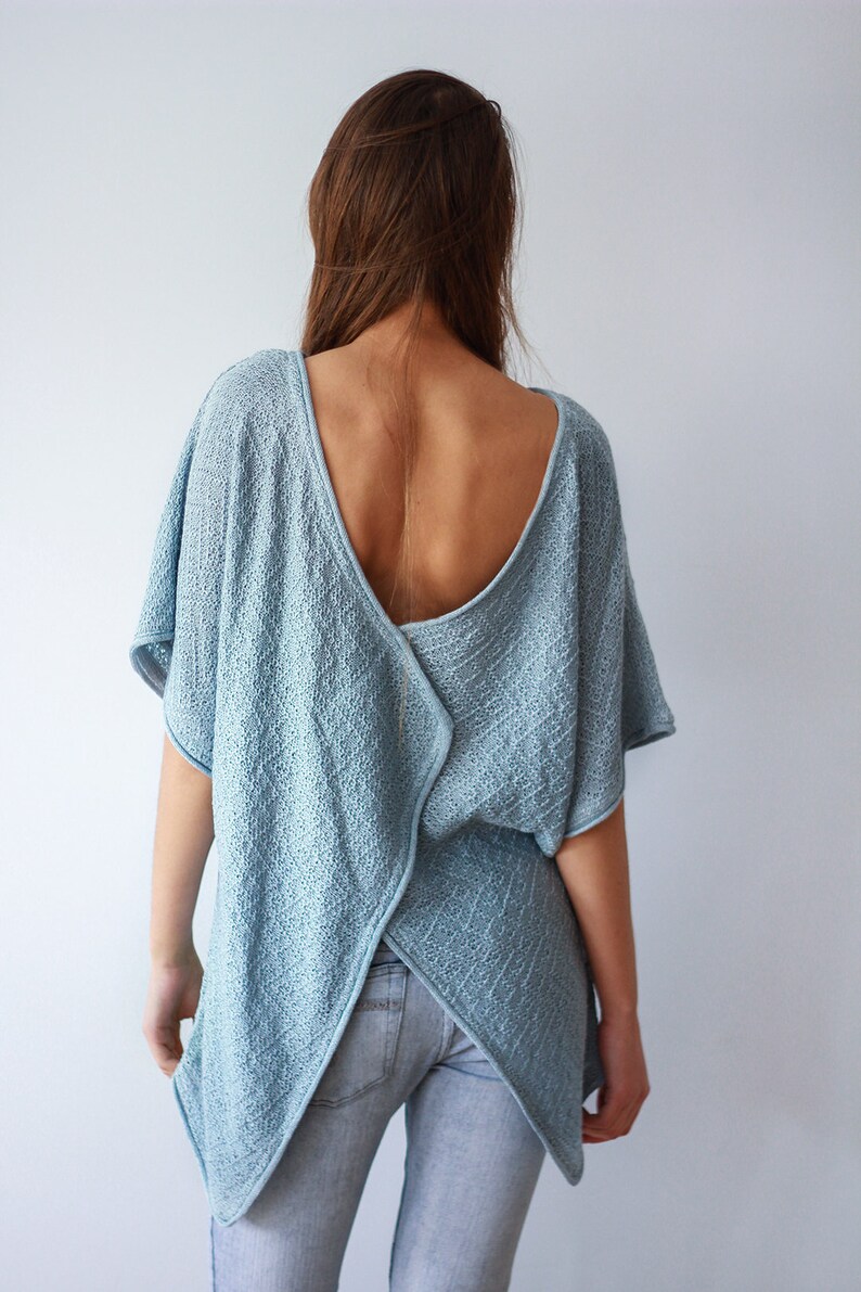 K&ouml;nnte beinhalten: Ein hellblaues Strickoberteil mit tiefem R&uuml;cken und einem Kreuzdesign im R&uuml;cken. Das Oberteil ist locker geschnitten und hat eine lockere Silhouette.
