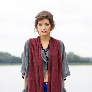 Peut inclure: Une femme portant un cardigan en tricot gris avec une &eacute;charpe en dentelle bordeaux, un jean bleu et un haut noir.