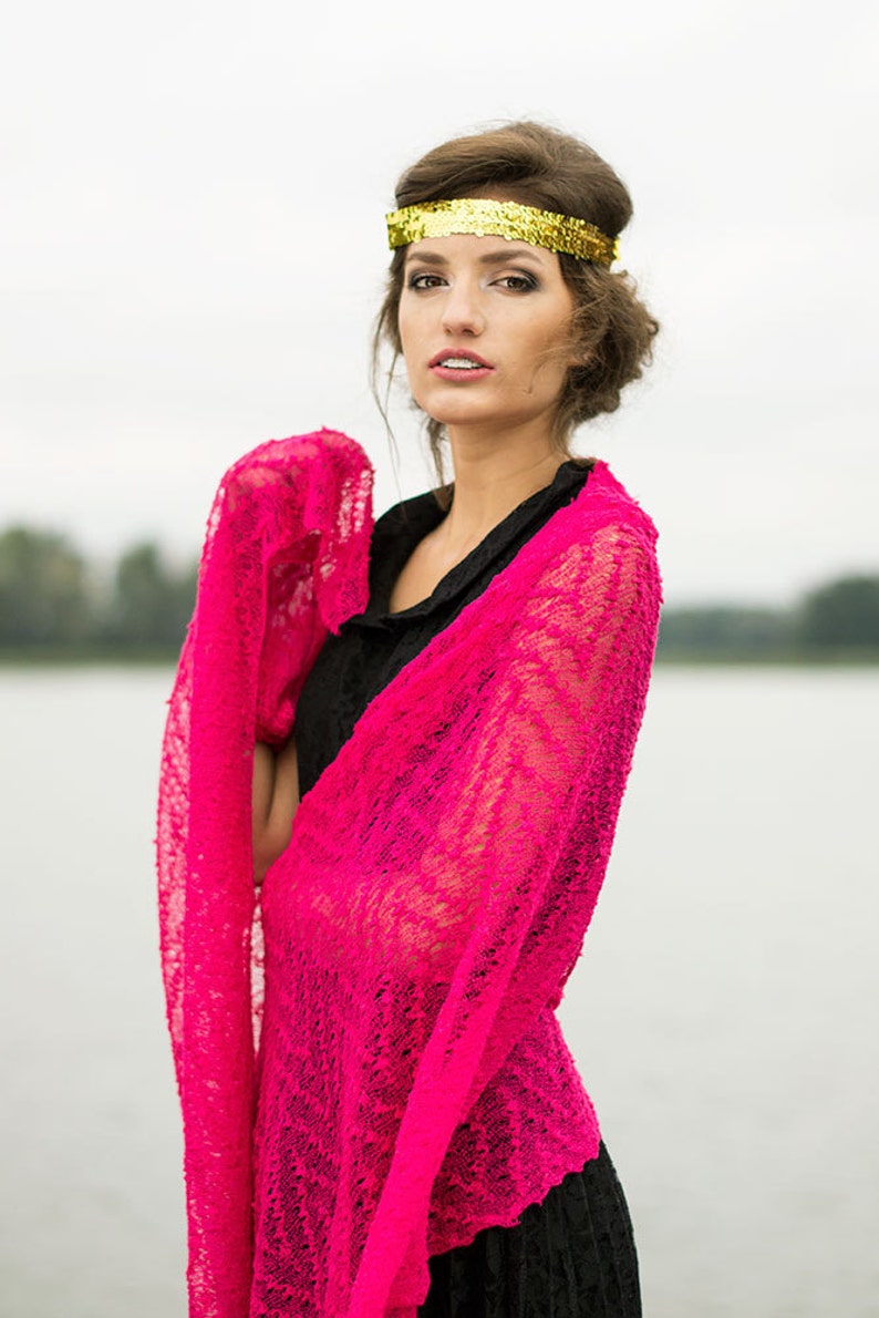 May include: A woman wearing a black dress with a pink lace shawl and a gold headband.