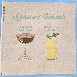 Op de afbeelding: Kruissteek canvas met twee cocktail illustraties: een Espresso Martini en een Kentucky Mule. De woorden "Signature Cocktails" staan boven de drankjes. De achtergrond is lichtbeige met een blauwe rand.