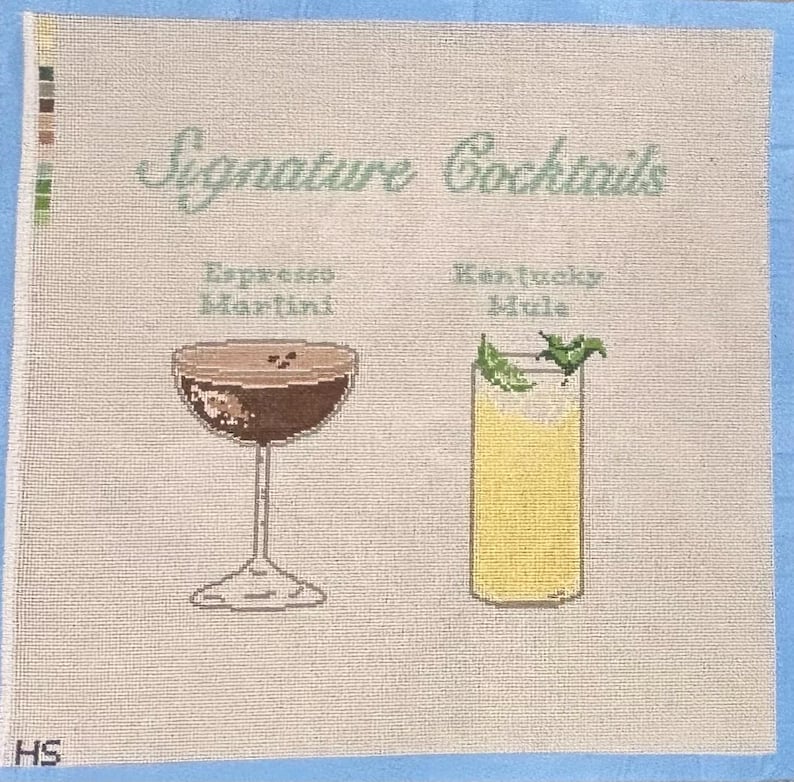 Op de afbeelding: Kruissteek canvas met twee cocktail illustraties: een Espresso Martini en een Kentucky Mule. De woorden "Signature Cocktails" staan boven de drankjes. De achtergrond is lichtbeige met een blauwe rand.