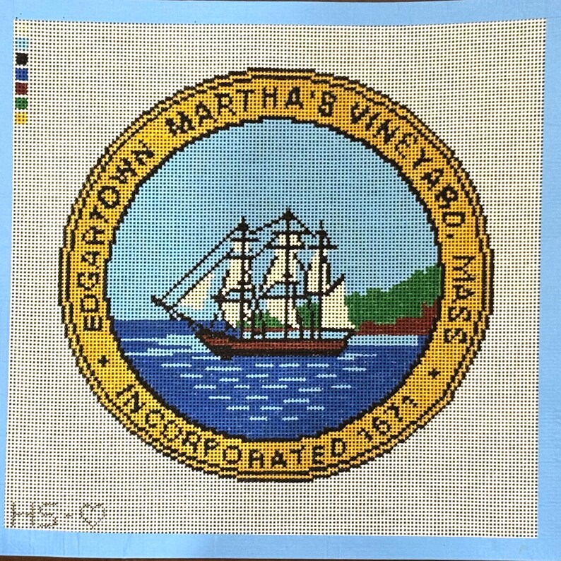 Op de afbeelding: Kruissteek van het zegel van Edgartown, Martha's Vineyard. Het ontwerp toont een zeilschip op blauw water, een groen eiland en de tekst "Edgartown Martha's Vineyard, Mass. Incorporated 1671" in een gouden cirkel.