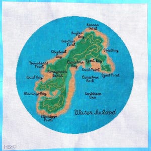 Op de afbeelding: Een handgestikte kaart van Water Island, met een groen eiland omringd door een blauwe oceaan. De kaart bevat plaatsnamen zoals Banana Point, Honeymoon Beach en Flamingo Bay. De tekst "Water Island" staat onderaan.
