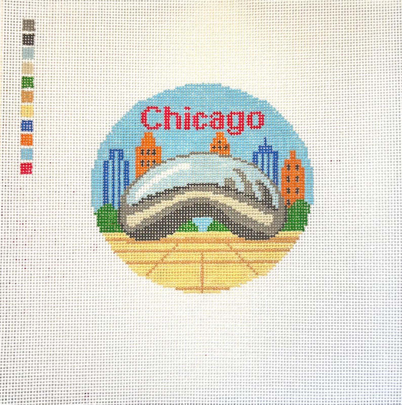 Op de afbeelding: Een borduurontwerp met de skyline van Chicago, inclusief de iconische Cloud Gate-sculptuur. Het woord "Chicago" is rood boven de sculptuur gestikt. De achtergrond is een lichtblauwe cirkel met oranje en blauwe gebouwen.