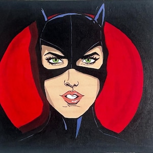 Puede incluir: Una pintura de estilo pop art de un personaje con una máscara negra con orejas de gato, ojos verdes y labios rojos. Un círculo rojo está detrás de la cabeza del personaje, sobre un fondo negro.