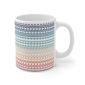 May include: White ceramic coffee mug with a decorative pattern of horizontal bands in shades of blue, green, orange, and red. The mug has a curved handle and a smooth, glossy finish. The design features various geometric shapes.