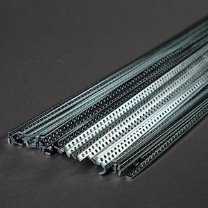 Könnte beinhalten: Eine Ansammlung silberfarbener Metallstreifen mit T-förmigem Querschnitt und einer Reihe gleichmäßig angeordneter, kreisförmiger Perforationen entlang der Länge jedes Stücks. Diese industriellen Bauteile sind in einem parallelen Bündel angeordnet.