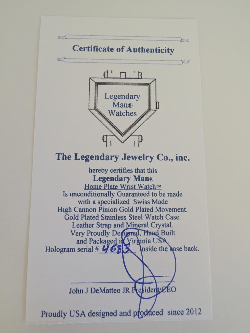 May include: A white Certificate of Authenticity for a Legendary Man Watches Home Plate Wrist Watch. The document features a line drawing of a home plate, blue text, and a handwritten hologram serial number 4683, signed by John J DeMatteo JR.