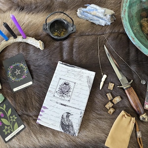May include: An assortment of mystical items on a brown fur-like surface. Includes tarot cards, a dagger, a small cauldron, a journal, a candle holder with candles, a pendulum, and rune stones. The items are in various colors.
