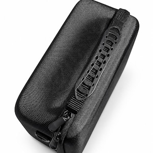 K&ouml;nnte beinhalten: Ein schwarzes, rechteckiges Etui mit strukturierter Oberfl&auml;che. Es verf&uuml;gt &uuml;ber einen schwarzen Rei&szlig;verschluss und einen Griff mit kleinen L&ouml;chern. Das Etui dient zum Schutz und Transport kleiner elektronischer Ger&auml;te oder Zubeh&ouml;rteile.