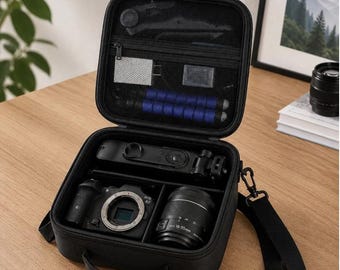 May include: Black camera case, open to reveal a camera, lens, and accessories. The case has a handle and a shoulder strap. The camera lens is labeled 18-55mm. The case is on a wooden surface.
