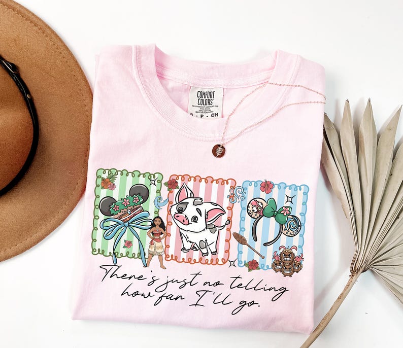 May include: A light pink t-shirt featuring a graphic print of a character, a pig, and two sets of mouse ears within three rectangular frames. Below the graphics, the text reads, "There's just no telling how far I'll go." The shirt has a Comfort Colors label.