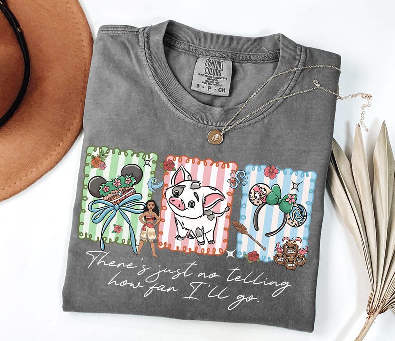 May include: A charcoal gray t-shirt featuring a graphic print of three rectangular panels with Moana, Pua the pig, and character-themed mouse ears. The text "There's just no telling how far I'll go" is printed in white script below the graphics.