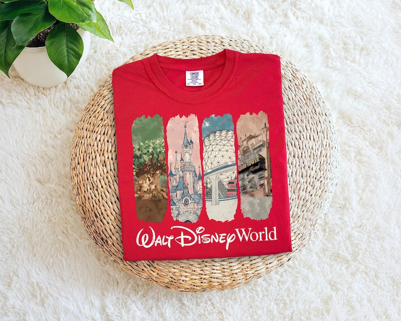 May include: Red crew neck t-shirt featuring four vertical rectangular panels with illustrations of Walt Disney World landmarks. The words "Walt Disney World" are printed in white script below the panels.