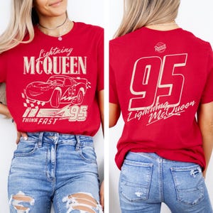 Pode incluir: Camiseta vermelha com Lightning McQueen do filme Carros. A frente mostra o personagem, o texto "Lightning McQueen" e "Think Fast". A parte de tr&aacute;s mostra o n&uacute;mero "95" e "Lightning McQueen".