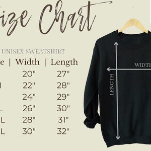 May include: A size chart for a unisex sweatshirt, with measurements in inches. The chart lists sizes S to 3XL, with corresponding width and length measurements. A black sweatshirt hangs on a wooden hanger, with arrows indicating width and length.