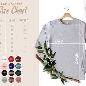 May include: A light gray long-sleeve shirt hanging on a wooden hanger, with a size chart and color swatches to the left. The size chart shows chest and length measurements in inches. The shirt is displayed with a sprig of greenery.