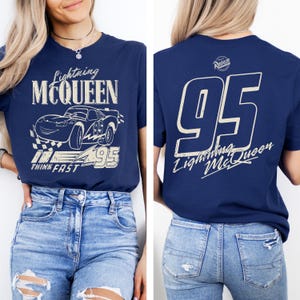 Pode incluir: Camiseta azul marinho com gr&aacute;ficos de Lightning McQueen. A frente mostra o carro com o texto "Lightning McQueen" e "Think Fast". A parte de tr&aacute;s mostra um grande "95" e o texto "Lightning McQueen".