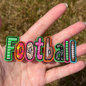 May include: An embroidered patch featuring the word Football in colorful, patterned letters. Each letter has a unique design, including green stripes, pink and orange floral, leopard print, pink glitter, brown football texture, and black stars.