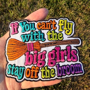 May include: A white embroidered patch with a black border featuring the text If You can't fly with the big girls Stay off the broom in multi-colored thread including pink, teal, orange, yellow, and purple, with an orange broomstick graphic.