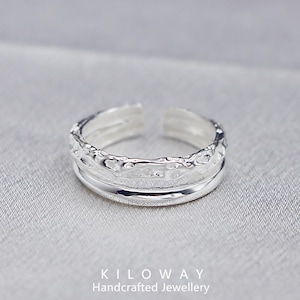 May include: A silver adjustable ring with a textured upper band and a smooth lower band. The ring is open at the front and sits on a grey surface. The text "KILOWAY Handcrafted Jewellery" is at the bottom.