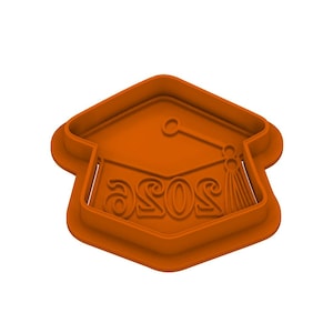 May include: An orange graduation cap-shaped cookie cutter. The word "ASOS" is embossed on the cap. The tassel and the cap's shape are clearly defined, making it ideal for creating graduation-themed cookies.