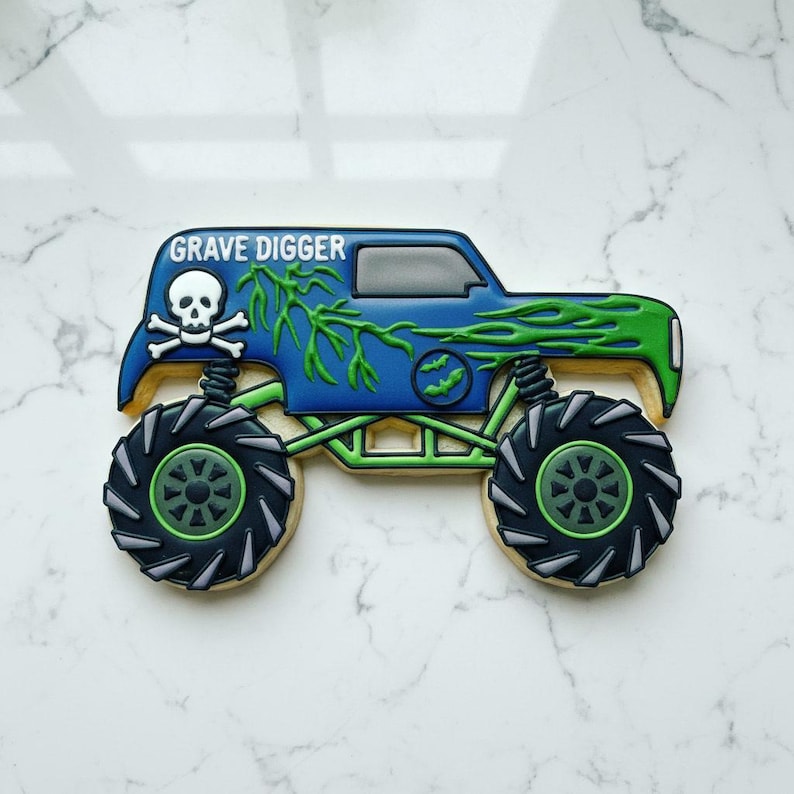 Blue and green monster truck royal icing cookie with oversized tires and spooky Grave Digger-inspired details on marble background.
