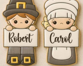 May include: Two Thanksgiving-themed biscuits, one depicting a pilgrim man holding a sign that reads "Robert", and the other a pilgrim woman holding a sign that reads "Carol". The biscuits are decorated with brown, grey, and yellow icing.