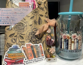 May include: A gift set for book lovers, featuring a floral-patterned package with a handwritten note, stickers, a bookmark, and a glass tumbler. The tumbler reads "Just a Girl Who Loves Books" and has a floral design.