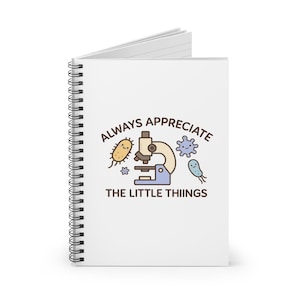 Könnte beinhalten: Ein weißes Spiralnotizbuch mit dem Text "ALWAYS APPRECIATE THE LITTLE THIINGS" und Illustrationen eines Mikroskops und Cartoon-Mikroben. Das Notizbuch ist offen und zeigt leere weiße Seiten.