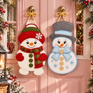 May include: Two felt snowman wall hangings suspended by yellow cords. The left snowman wears a red hat with a green brim, a red and green plaid scarf, and three green buttons. The right snowman wears a gray top hat, a light blue bow, and three tan buttons.