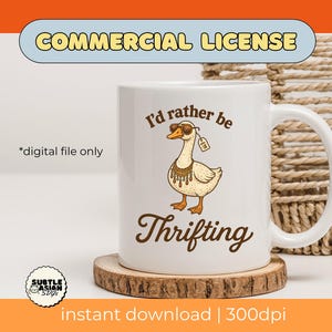 Op de afbeelding: Witte keramische mok met een cartoon gans met een zonnebril en een label, met de tekst "I'd rather be Thrifting". De mok staat op een houten onderzetter. De tekst "COMMERCIAL LICENSE" staat bovenaan.