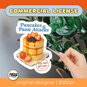 May include: A sticker showing a stack of pancakes with strawberries and dark brown pearls, and the text "Pancakes & Panic Attacks." The sticker includes a "buy one, get one" offer and a "Commercial License" label.
