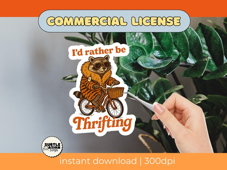 May include: A sticker featuring a raccoon wearing sunglasses and a fur-trimmed coat, riding a bicycle with a basket. The text reads "I'd rather be Thrifting." The sticker has a "Commercial License" label.