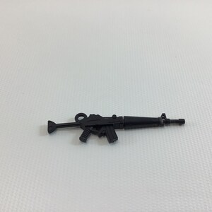 May include: A black plastic toy assault rifle. The rifle has a black barrel, a black handle, and a black magazine.