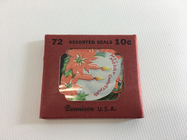 K&ouml;nnte beinhalten: Eine rote Pappbox mit einem durchsichtigen Plastikfenster, in dem verschiedene Weihnachtssticker zu sehen sind. Auf der Box steht "72 Assorted Seals 10c" und "Dennison U.S.A.".