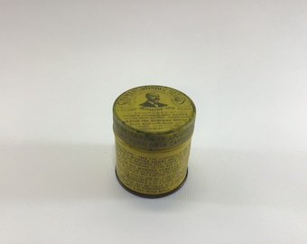 May include: A yellow metal tin with a black and white image of a man on the lid. The text on the lid reads "Whans Wonder Herbs A Blood Medicine and Tonic Roots Here and Barks A Boon for Suffering Women To be Taken in Liquid Form or in Capsules".