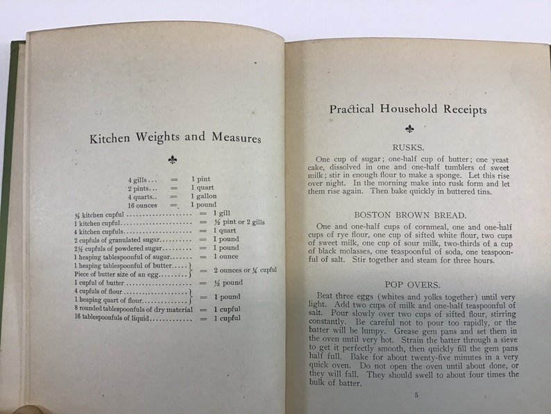 May include: A vintage cookbook with a cream-colored cover and black text. The title is "Practical Household Receipts" and the subtitle is "Kitchen Weights and Measures". The book includes recipes for rusks, Boston brown bread, and pop overs.