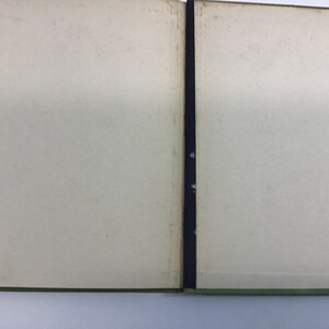 May include: An open book with blank pages and a green cover. The book is bound with a black ribbon.