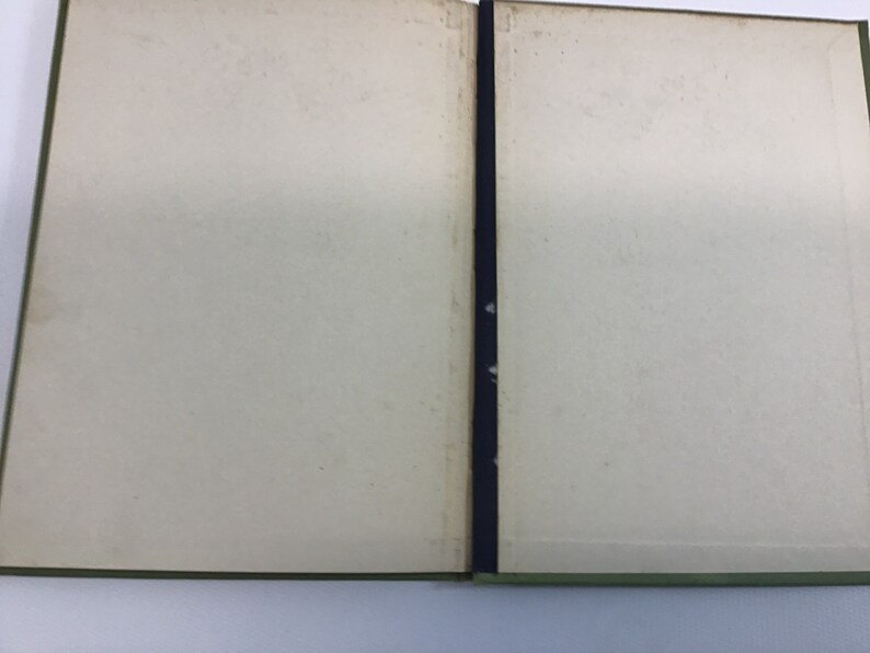 May include: An open book with blank pages and a green cover. The book is bound with a black ribbon.