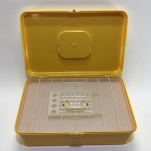 May include: A yellow plastic storage box with a clear lid and a removable tray with multiple compartments. The box is open and the tray is visible.