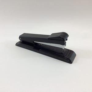 May include: A black stapler, a common office supply, is shown against a white background. The stapler has a sleek, modern design with a black body and a silver staple guide. It is a standard size, suitable for everyday use.