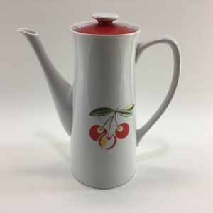 May include: White ceramic coffee pot with a red lid and a cherry design. The cherries are red with yellow centers and green leaves.