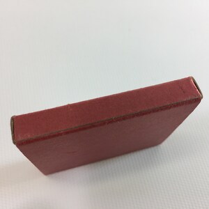 K&ouml;nnte beinhalten: Eine rote Schachtel aus Pappe mit einem leicht erh&ouml;hten Rand um die Oberseite.